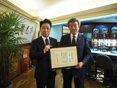 表彰状を手にする市長と男性