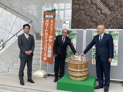 募金用の樽を囲む3人のスーツの男性